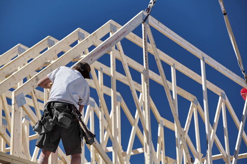 Construction carpenter man setting roof trusts into place